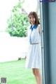 A woman in a blue and white dress leaning against a wall.